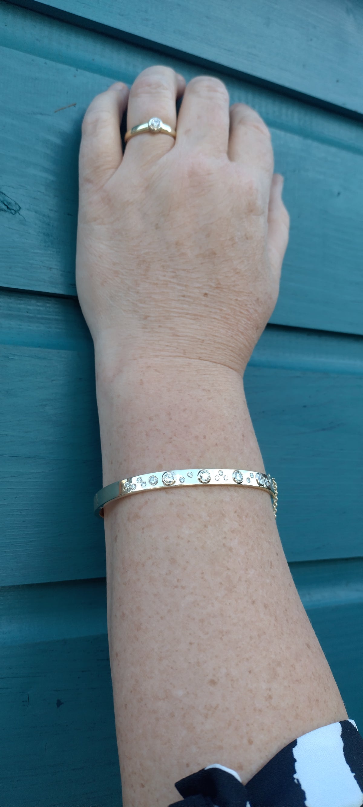 Custom made 9ct gold and diamond bangle worn on the wrist, with a gold and diamond ring.